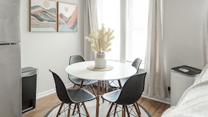 A modern kitchen with a refrigerator, a dining table with chairs, and a window with curtains. - Stylish and Comfy Studio near Loyola Park (Chicago)