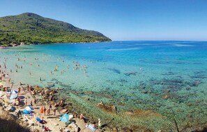A crowded beach with clear water, rocky shore, and a mountain in the background. - Lovely home in Giungano with house a panoramic view (Giungano)