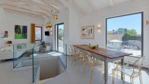 Un intérieur moderne avec un coin repas, des rampes en verre et une vue sur l’extérieur.