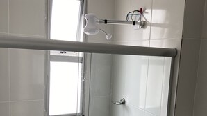 Et brusebad med glasdør, håndklædestang og et vindue.