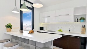 Una cocina moderna con una isla central, taburetes de bar, un ventanal con vistas a la ciudad y un microondas empotrado.