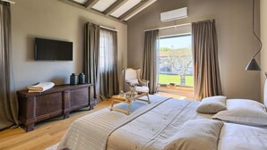 Ein Schlafzimmer mit einem großen Bett, einem hölzernen Schminktisch, einem Sessel und einem Fernseher an der Wand.