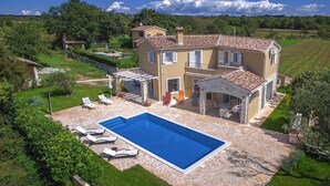 Ein zweistöckiges Haus mit Swimmingpool, Sitzgelegenheiten im Freien und einem Garten.