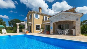 Ein zweistöckiges Haus mit Pool, Sitzgelegenheiten im Freien und einem steinernen Bogen.