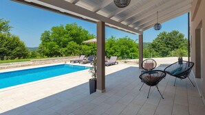 A covered outdoor area with a swimming pool, lounge chairs, and a pergola with hanging lights. - Awesome home in Pazin with sauna (Pazin)