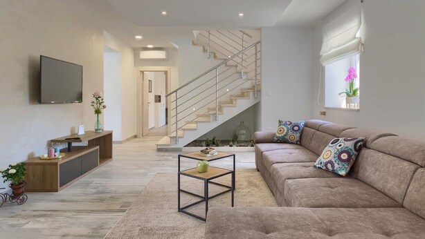 A modern living room with a sofa, coffee table, and a TV mounted on the wall. - Awesome home in Pazin with sauna (Pazin)