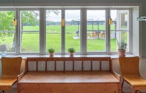 A bench with a view of a grassy yard through large windows. - 4 bedroom awesome home in Jönköping (Jönköping)