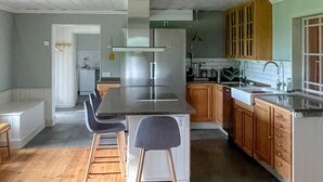 Une cuisine moderne dotée d’un îlot central, de tabourets de bar, d’armoires en bois et d’un réfrigérateur en acier inoxydable.