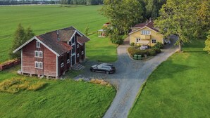 Une propriété rurale comprenant une grande grange, une maison jaune et une allée gravillonnée.