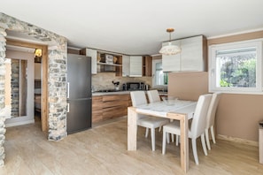 A modern kitchen with a stone wall, wooden cabinets, a stainless steel refrigerator, and a dining area with a marble table and chairs. - Exceptional apartment of approximately 50 m2, located on the ground floor of a residential complex along the coast of the Gulf of Poets! The accommodation offers sea view, private garden, 2 bedrooms and outdoor dining area!The apartment is located in Fia (Tellaro, Lerici)