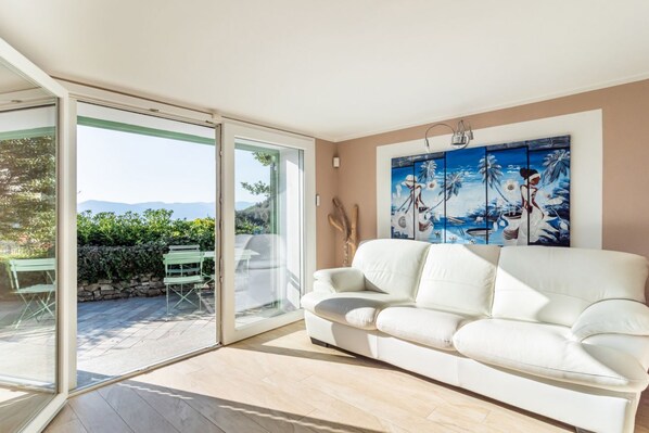 A white sofa in a room with a sliding glass door leading to an outdoor patio.