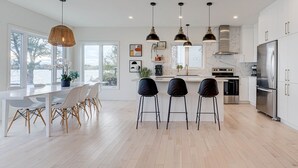A modern kitchen with white cabinets, a stainless steel refrigerator, and pendant lights.