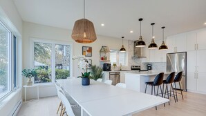 A modern kitchen with white cabinets, a large island, and pendant lighting.