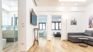 Ein modernes Wohnzimmer mit einer Couch, einem Fernseher und einer Stehlampe.