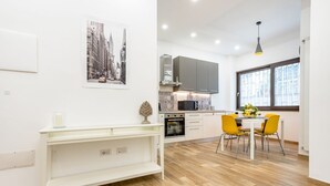 Eine moderne Küche mit Mikrowelle, Backofen und Schränken, ein Essbereich mit Tisch und Stühlen sowie ein großes Fenster.