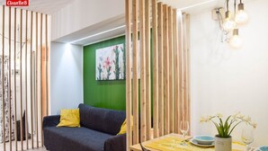 Una habitación con un sofá, una mesa de comedor y una pared verde con una pintura floral.