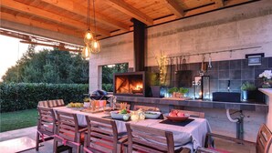An outdoor kitchen with a grill, dining table, and chairs. - Awesome home in Svetvincenat (Svetvincenat)