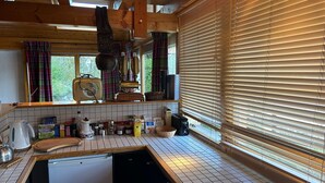 Una cocina con lavavajillas, una radio antigua y una ventana con persianas.