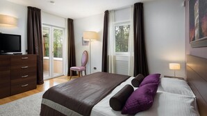 Une chambre moderne avec un grand lit, une télévision, un fauteuil et un bureau.