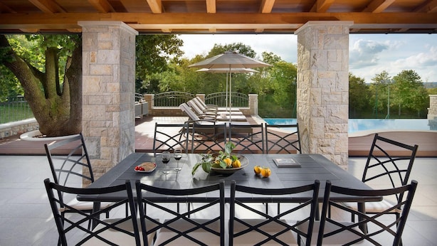 Une terrasse extérieure avec une table à manger, des chaises et une piscine en arrière-plan.