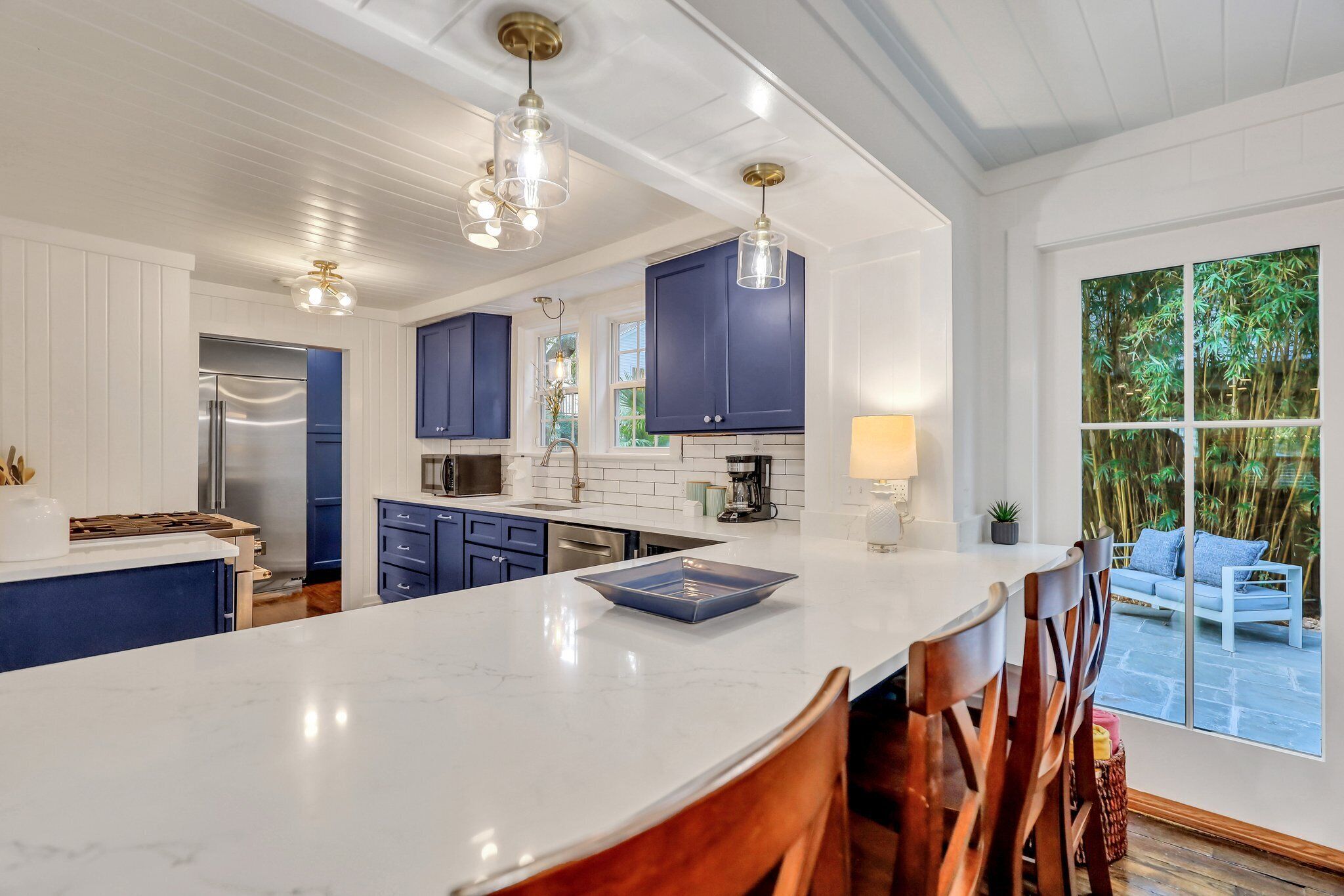 A modern kitchen with white cabinetry, a marble island, and pendant lighting.