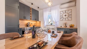 A modern kitchen with grey cabinets, a wooden countertop, and a dining area with a long table and brown chairs.