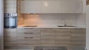 Eine moderne Küche mit eingebautem Backofen, einer Spüle und Holzschränken.