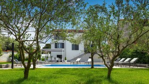 Ein modernes, zweistöckiges Haus mit Swimmingpool, Außenbereich und einem gepflegten Garten.