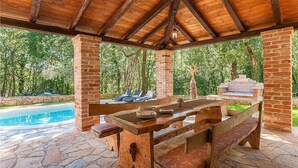 A wooden outdoor patio with a pool, stone flooring, and a brick barbecue area. - Amazing home in Tinjan (Tinjan)