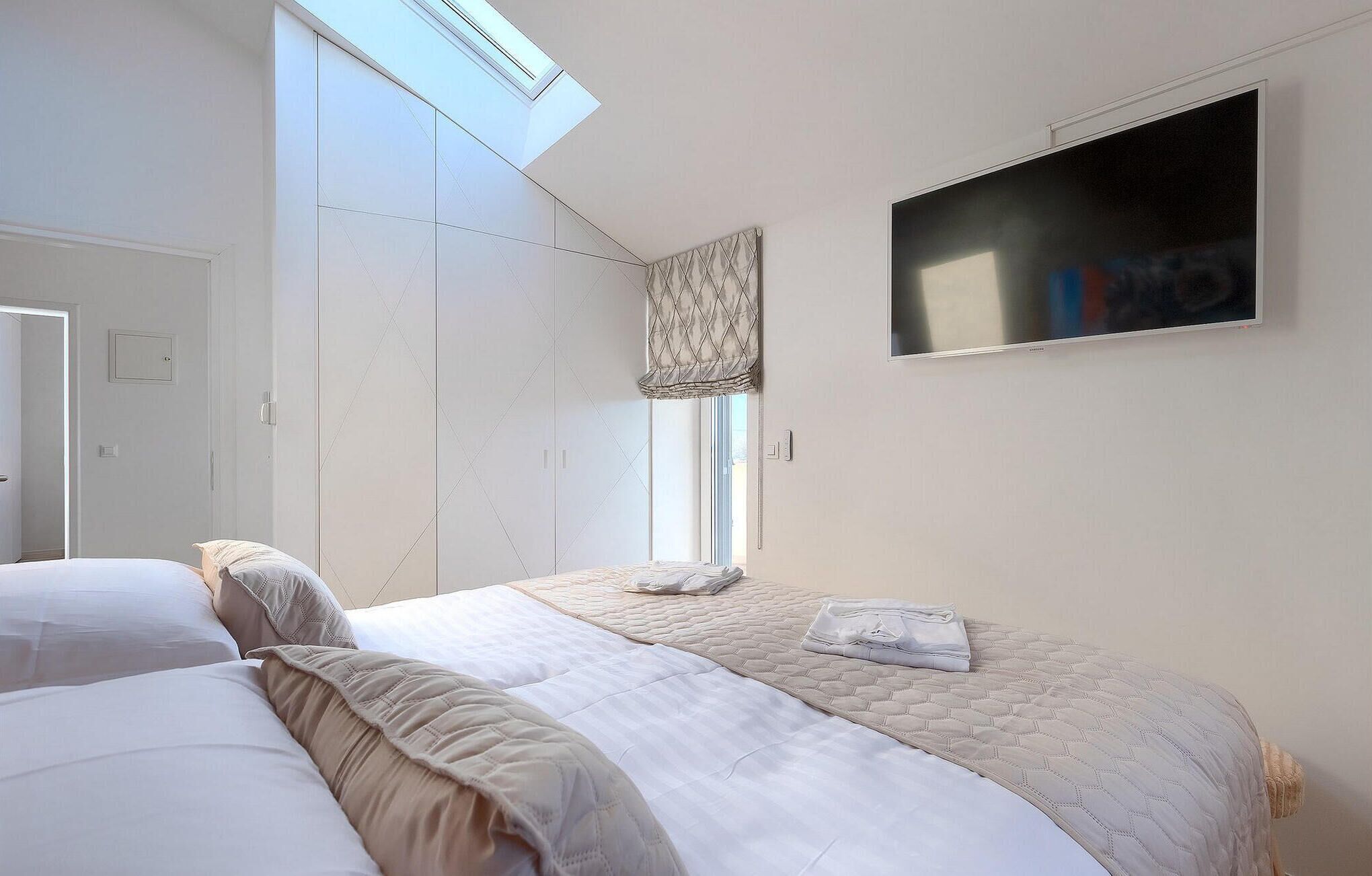 Une chambre à coucher avec un lit, une télévision, une armoire et une fenêtre avec des rideaux.