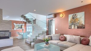 Una sala de estar moderna con una escalera de cristal, un conjunto de sofás y un cuadro en la pared.