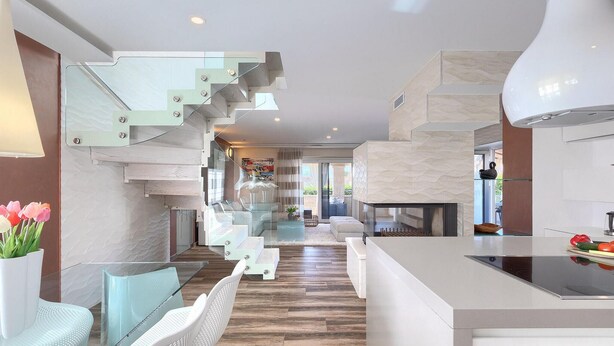 Un interior moderno con una escalera, una zona de estar y una cocina.