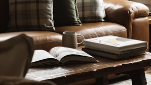 A cozy living room with a leather sofa, a coffee table, and a vase of dried flowers. - Cosy Retreat with Mountain Views (Warburton)