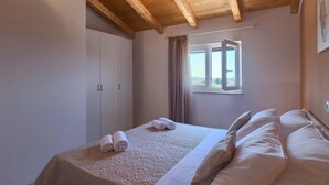 A bedroom with a wooden ceiling, a bed with white linens, a window with curtains, and a view of the outdoors. - Awesome home in Fazana (Fazana)
