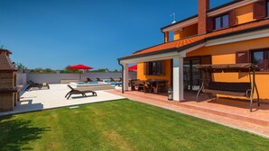 Una propiedad residencial con piscina, mobiliario de exterior y un césped bien cuidado.