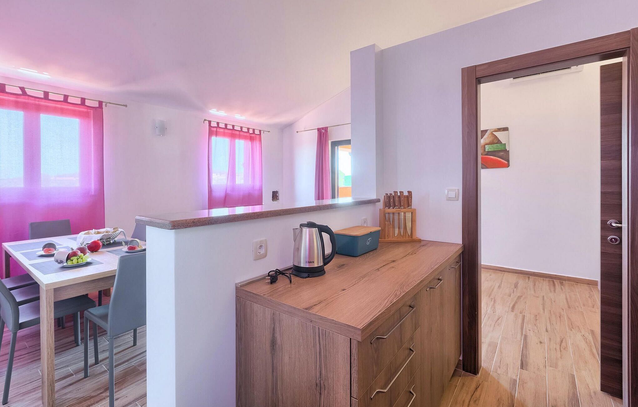 A compact kitchen with a wooden countertop, a kettle, and a knife block.