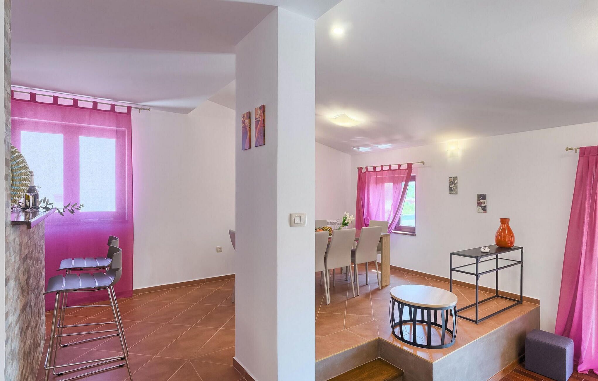 A modern living space with a dining area, kitchen, and a staircase.