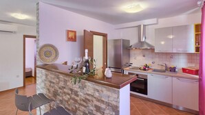 Una cocina moderna con una isla central, electrodomésticos de acero inoxidable y un salpicadero de azulejos.