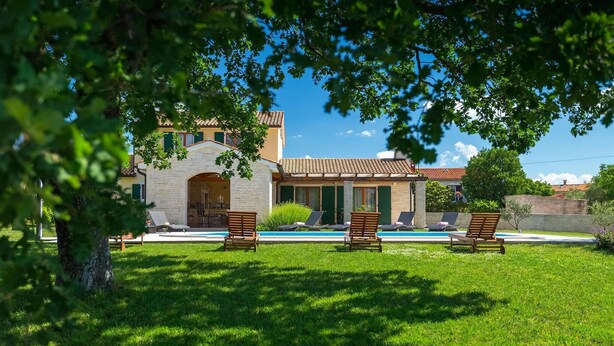 Eine Villa mit Swimmingpool, Sitzgelegenheit im Freien und einem steinernen Bogen.