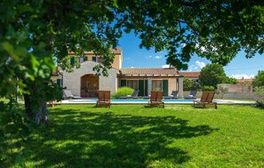 Una villa con piscina, mobiliario exterior y un arco de piedra.