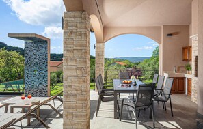 Une terrasse avec une table et des chaises, un pilier en pierre et une vue sur le paysage.