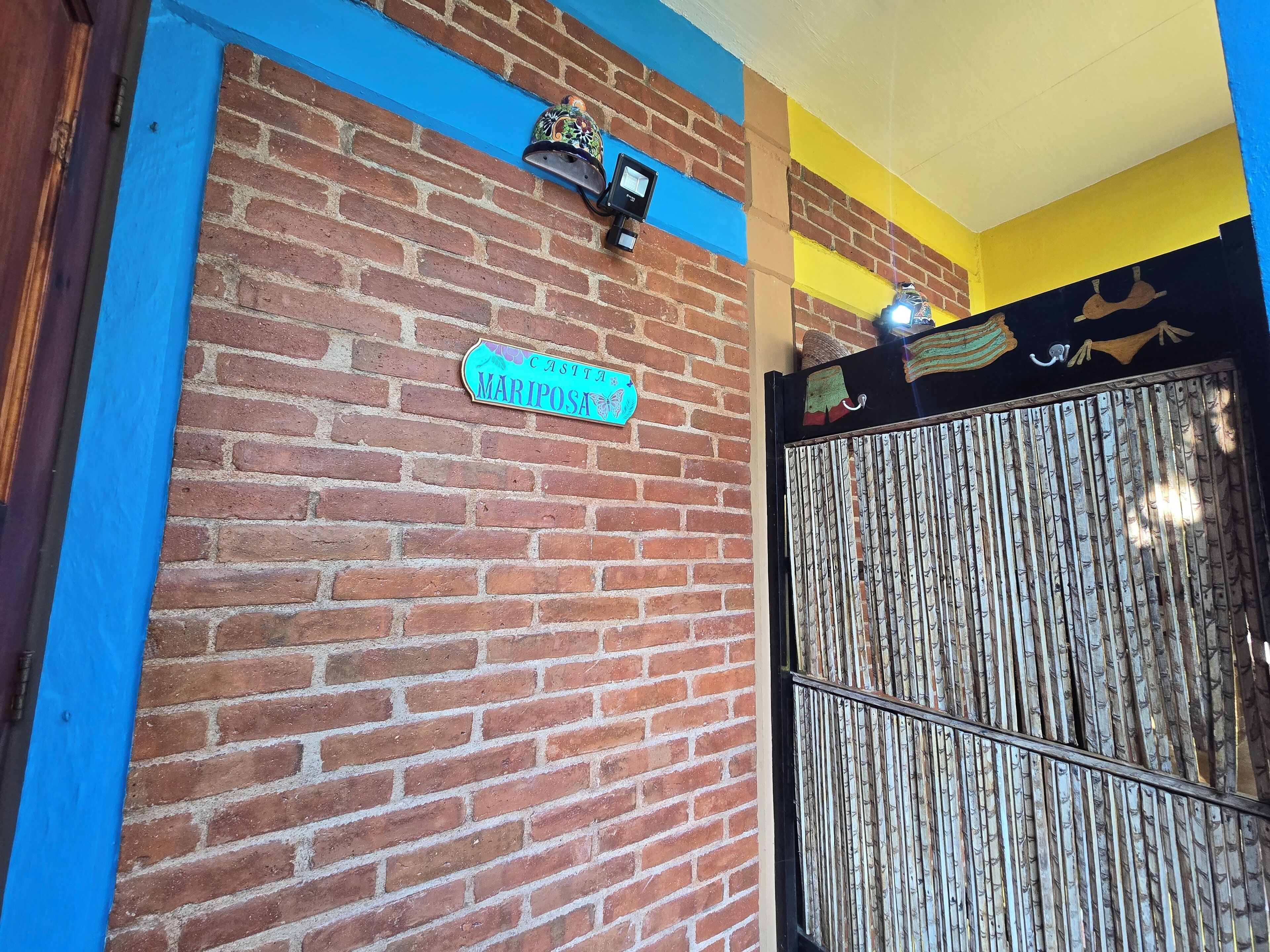 A brick wall with a sign reading "CASTA MARIPOSA" and a decorative bell.