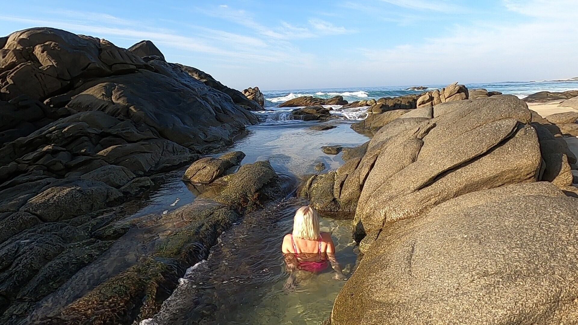 A rocky beach with large boulders and a clear view of the ocean.