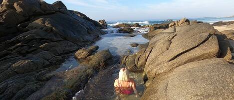 A rocky beach with large boulders and a clear view of the ocean.