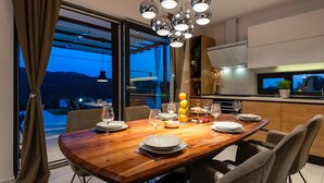 A dining area with a wooden table set for four, a kitchen with a TV, and a view of the outdoors. - Pet friendly home in Sibenik (Sibenik)