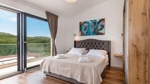 A bedroom with a large bed, a view of greenery through a sliding glass door, and a painting on the wall. - Pet friendly home in Sibenik (Sibenik)