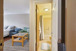 A hotel room with a bed, a sofa, a coffee table, and a bathroom visible through an open door. - Schuss Mountain Ski/Golf Condo (Mancelona)