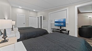 Una habitación de hotel con dos camas, un escritorio, un televisor y una lámpara.