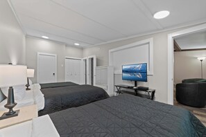 Una habitación de hotel con dos camas, un escritorio, un televisor y una lámpara.