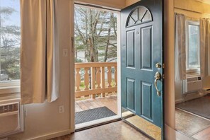 A door leading to a balcony with a view of trees and a wooden deck. - Schuss Mountain Ski/Golf Condo (Mancelona)